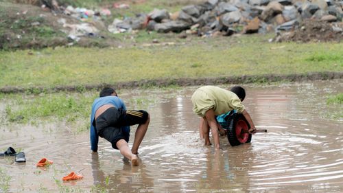 small,boys,playing,dirty,water,paddy,fieldthe,field,building