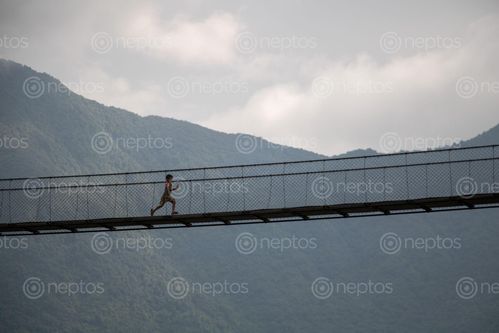 Find  the Image kid,running,suspension,bridge  and other Royalty Free Stock Images of Nepal in the Neptos collection.